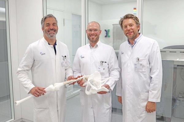 Drei Ärzte im weißen Kittel mit einem Knochenmodell aus dem 3D-Drucker